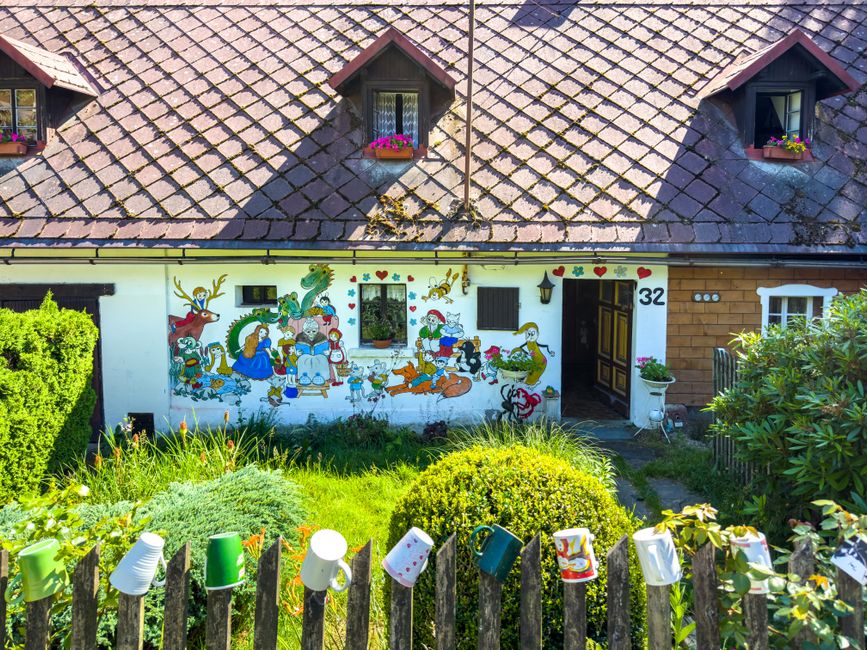 Picturesque cottage in Liberecký kraj, Czech Republic, with a colorful mural and front yard flowers.